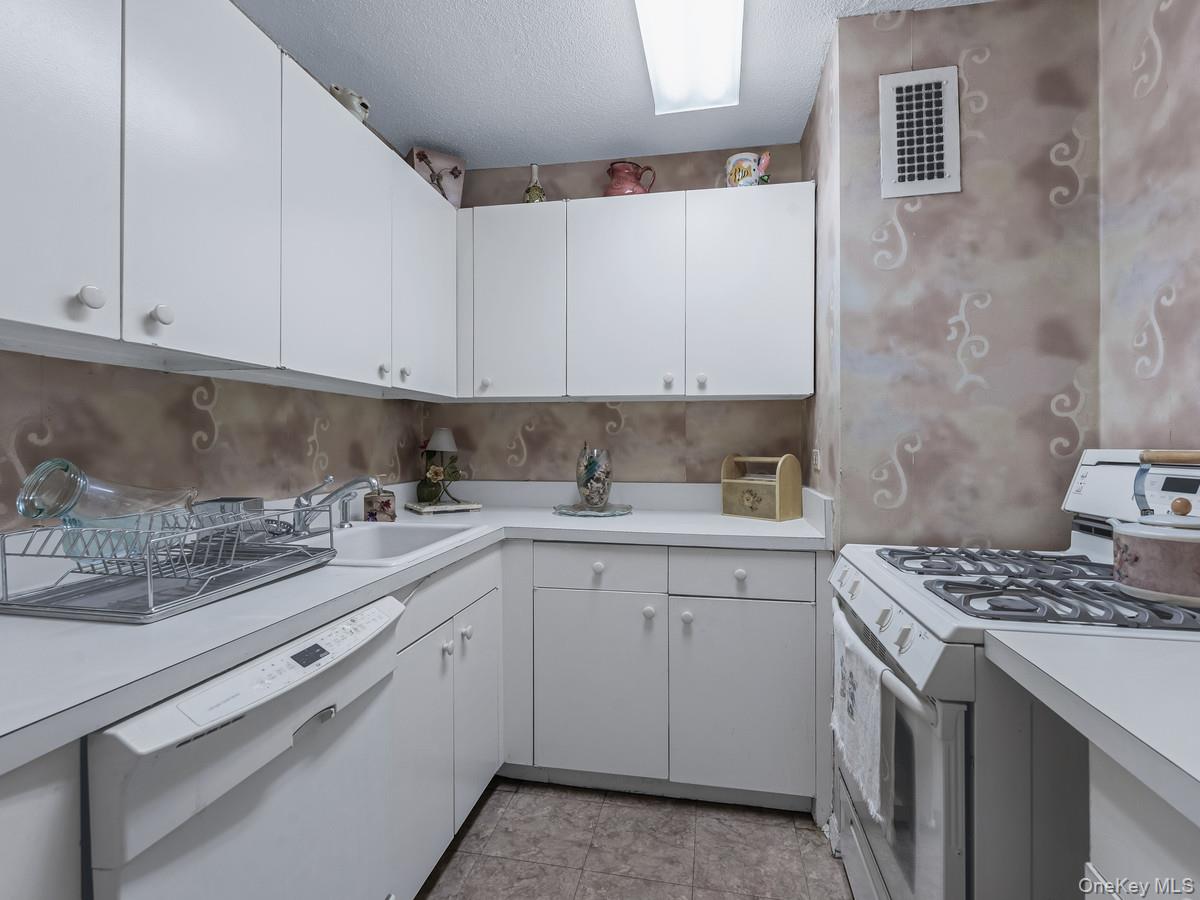77 Fulton Street, Unit 19C Manhattan, NY 10038 - Photo 5 of 20 a kitchen with stainless steel appliances granite countertop a sink stove and cabinets