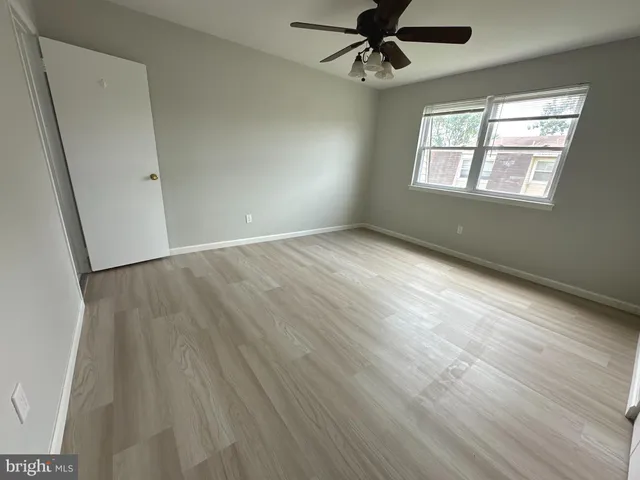 an empty room with wooden floor fan and windows