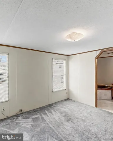a view of empty room with wooden floor and kitchen view