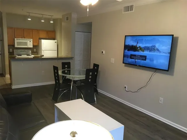 a kitchen with a table chairs refrigerator and wooden floor