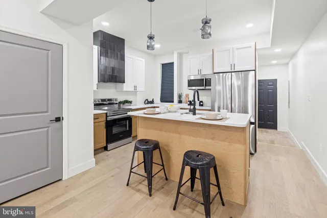 a kitchen with stainless steel appliances granite countertop a table chairs refrigerator and microwave