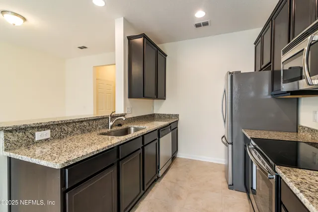 a kitchen with stainless steel appliances granite countertop a sink and a refrigerator