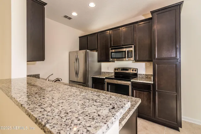 a kitchen with granite countertop a refrigerator and a stove top oven