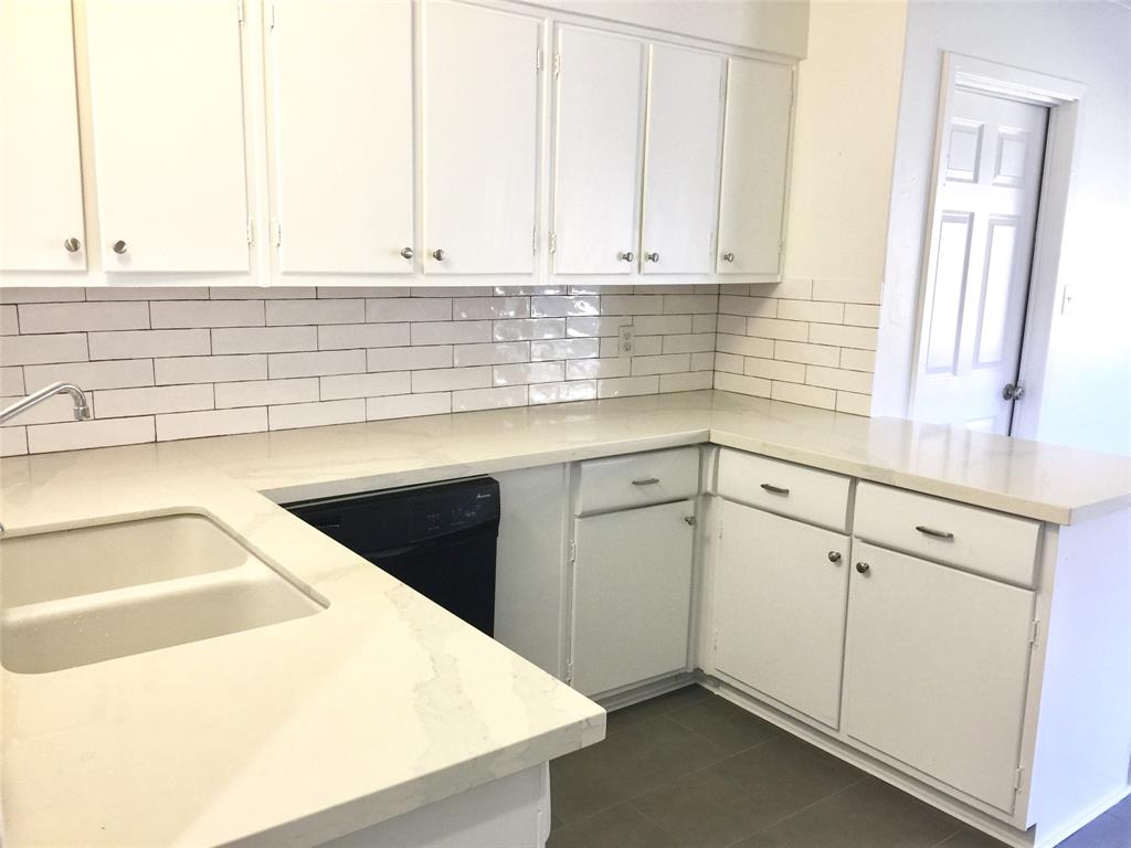 Freshly updated kitchen with attractive tile and solid surface counters.