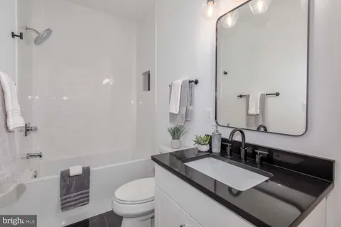 a bathroom with a granite countertop sink and a mirror a toilet