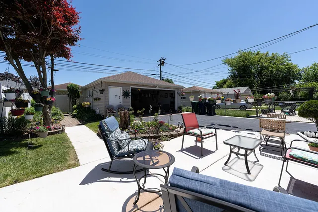 a view of a patio with table and chairs potted plants and a large tree