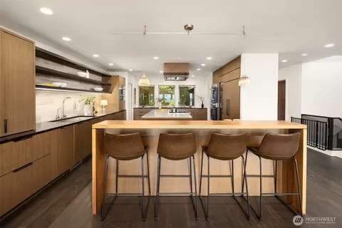 a kitchen with granite countertop a dining table chairs cabinets and stainless steel appliances