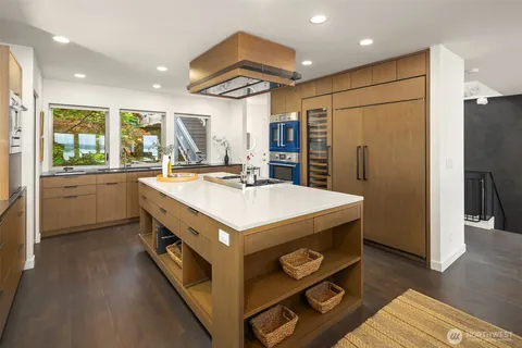 a kitchen with kitchen island a counter top a sink a refrigerator and wooden cabinets