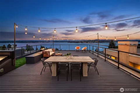 a view of a roof deck with table and chairs a barbeque with wooden floor and fence