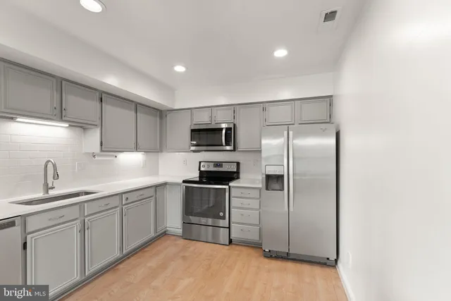 a kitchen with stainless steel appliances granite countertop a sink a stove a refrigerator a microwave a sink and cabinets