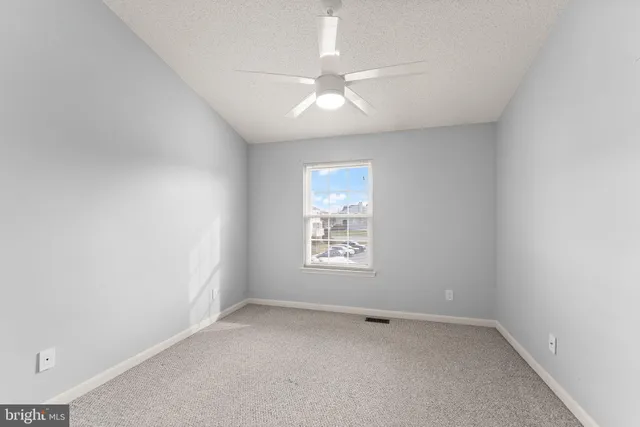an empty room with a window and a fan