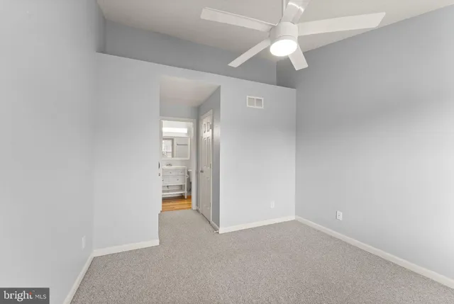 an empty room with a ceiling fan and a bathroom