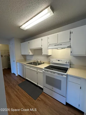 a kitchen with granite countertop a stove cabinets and wooden floor