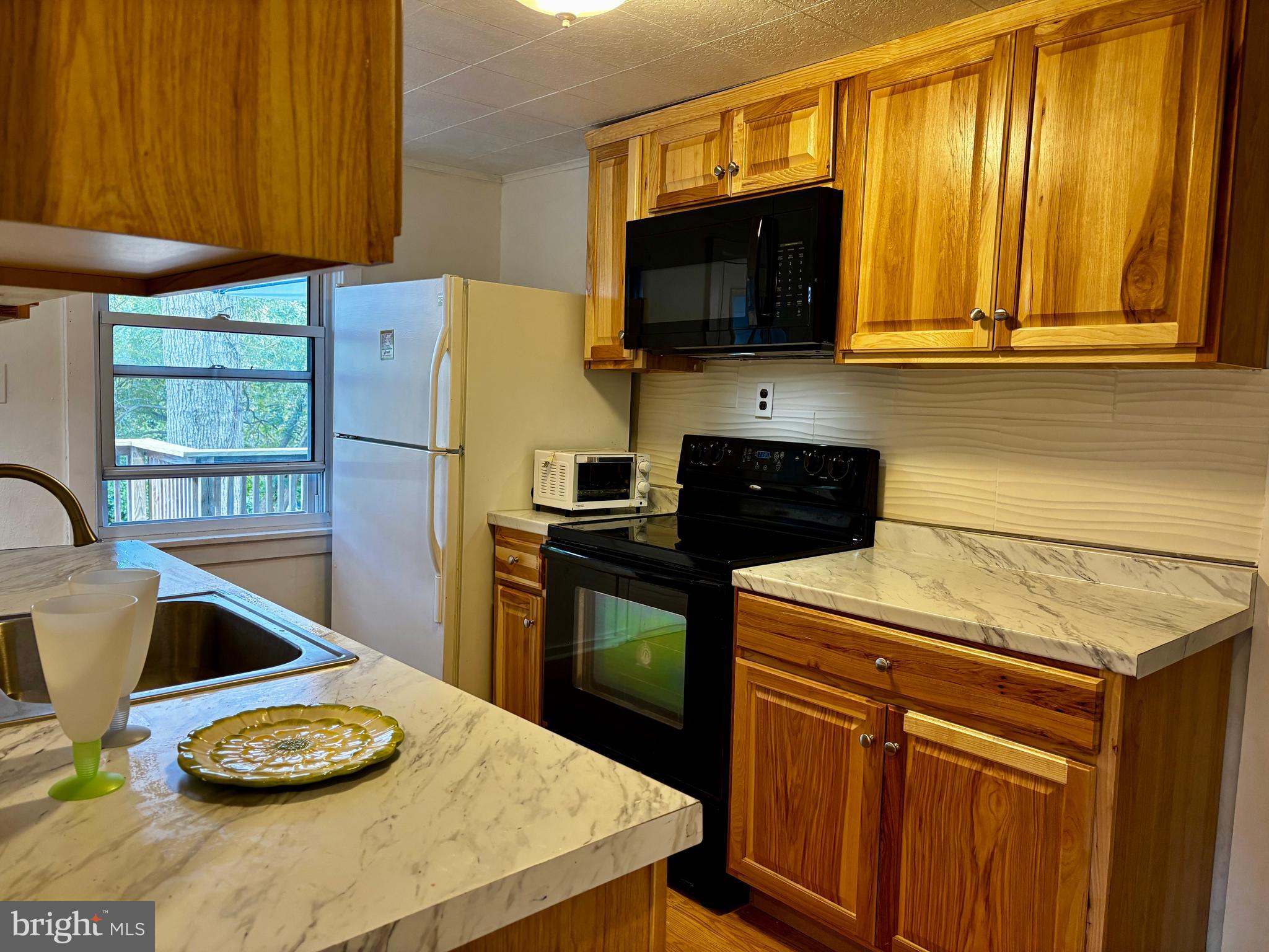 2044 Mill Road Norristown, PA 19403 - Photo 4 of 55 a kitchen with stainless steel appliances a stove a microwave and wood cabinets
