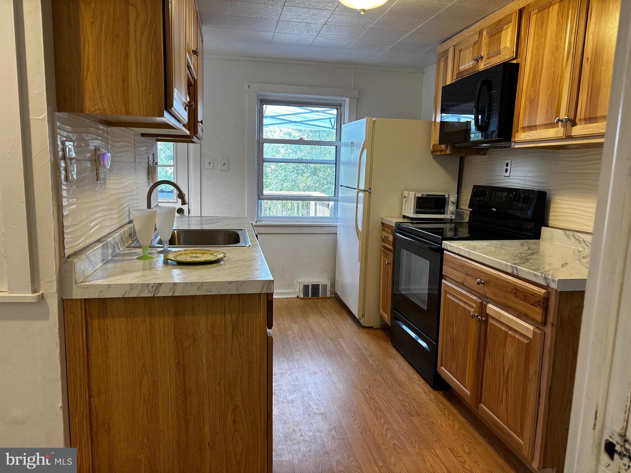 2044 Mill Road Norristown, PA 19403 - Photo 5 of 55 a kitchen with stainless steel appliances granite countertop a stove a sink dishwasher and a microwave oven with wooden cabinets