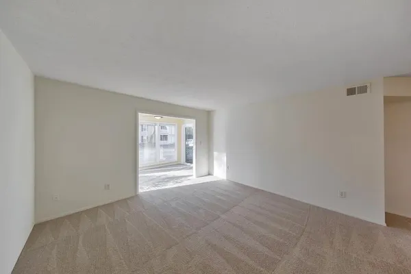 a view of an empty room with a window and a kitchen