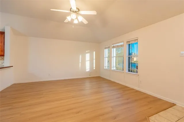 a view of an empty room with window and a kitchen