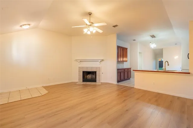 a view of an empty room with chandelier fan and fire place