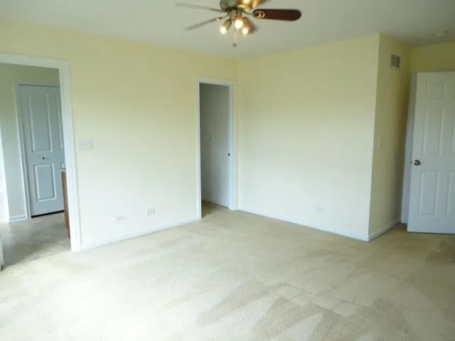 an empty room with a ceiling fan and carpet