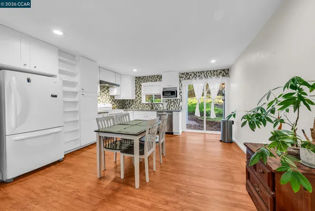a kitchen with stainless steel appliances a dining table chairs refrigerator and sink