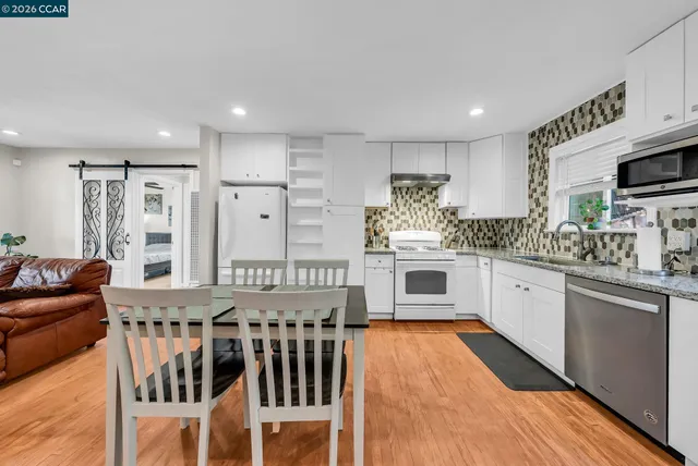 a kitchen with stainless steel appliances kitchen island granite countertop a stove and white cabinets