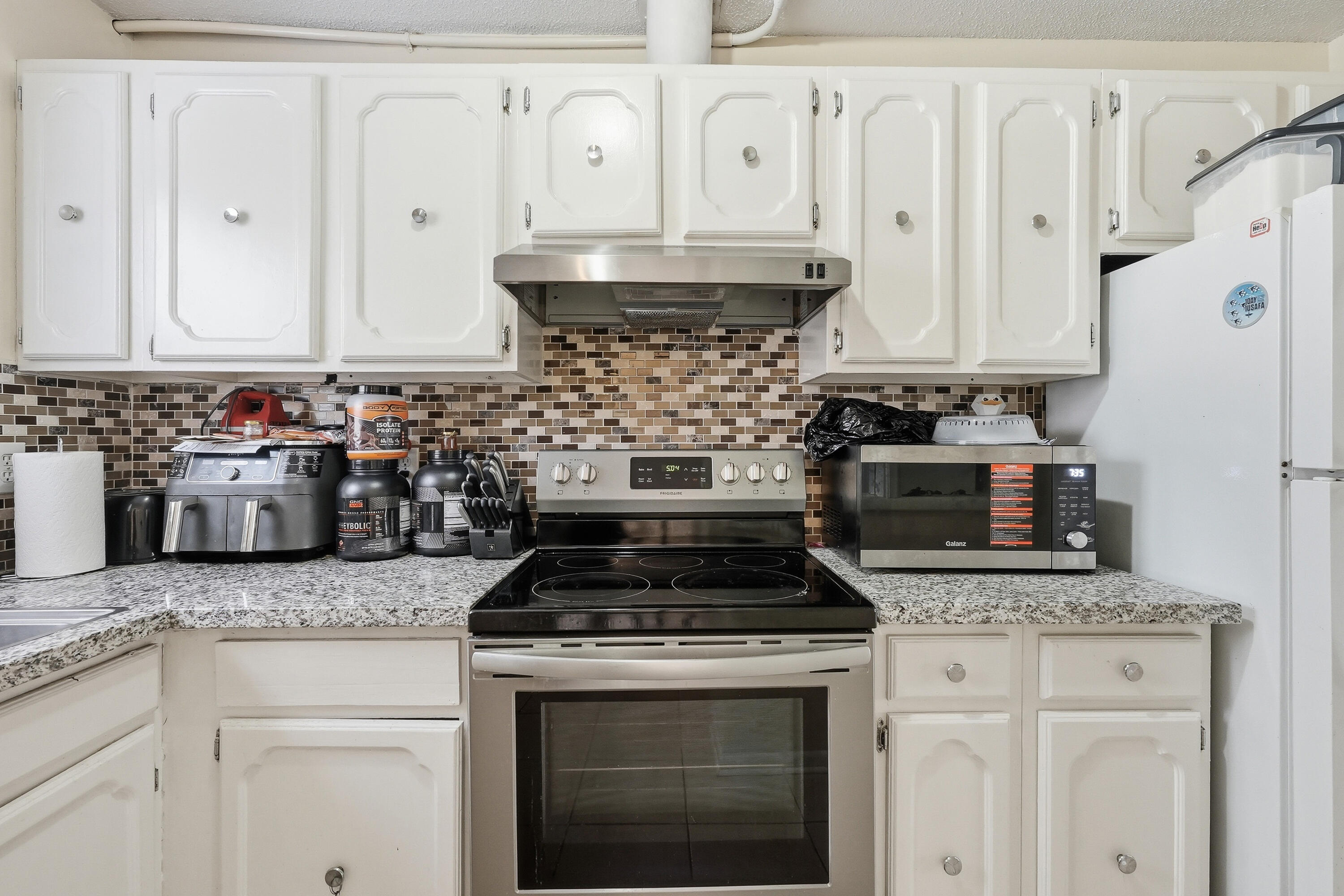 41 12th Street, Unit 68 Shalimar, FL 32579 - Photo 3 of 32 a kitchen with granite countertop white cabinets and stainless steel appliances