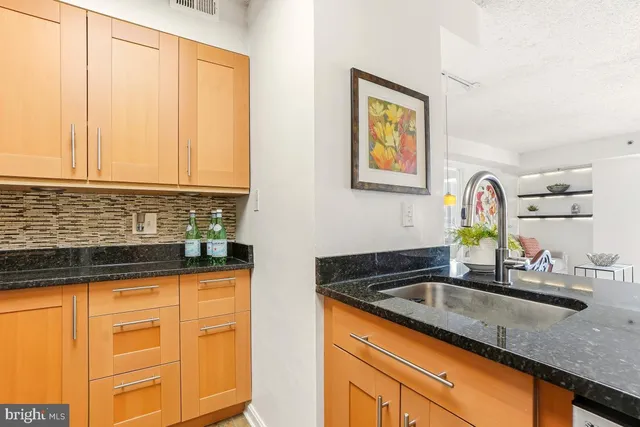a kitchen with granite countertop a sink a stove and cabinets
