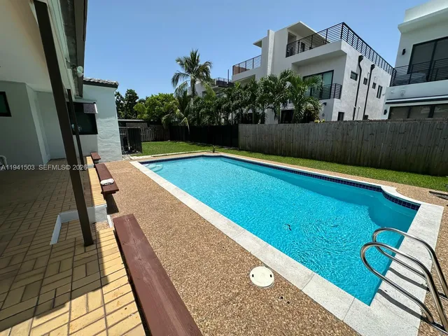 a view of swimming pool with seating space and trees in the background