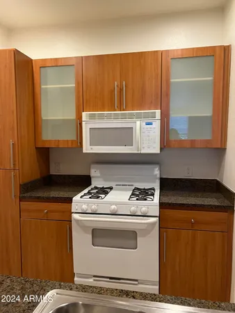 a kitchen with granite countertop a stove a sink and a microwave