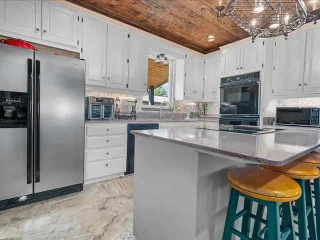 a kitchen with granite countertop a refrigerator stove and white cabinets