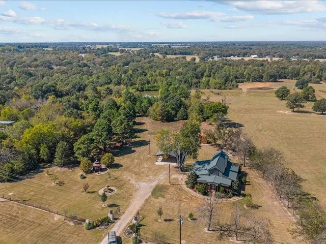 an aerial view of a residential houses with outdoor space and trees all around