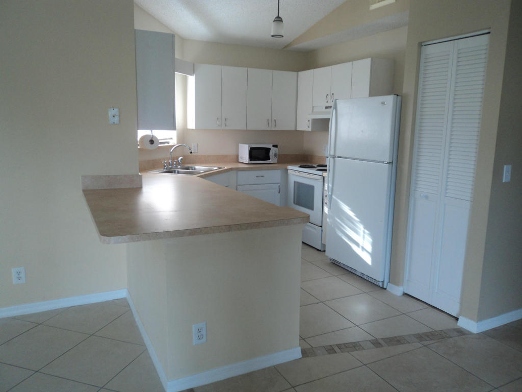 2827 Stoneway Lane, Unit D Fort Pierce, FL 34982 - Photo 5 of 25 a kitchen with stainless steel appliances granite countertop a refrigerator sink and white cabinets