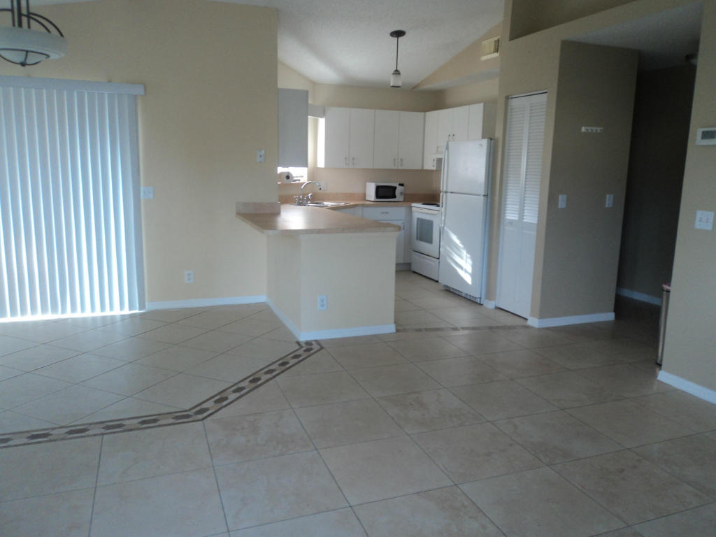 2827 Stoneway Lane, Unit D Fort Pierce, FL 34982 - Photo 6 of 25 a kitchen with stainless steel appliances granite countertop a refrigerator a sink a stove and white cabinets