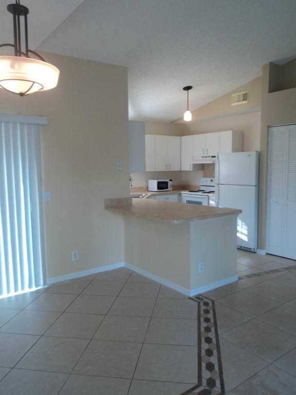 2827 Stoneway Lane, Unit D Fort Pierce, FL 34982 - Photo 7 of 25 a kitchen with kitchen island granite countertop a sink a counter top space and cabinets