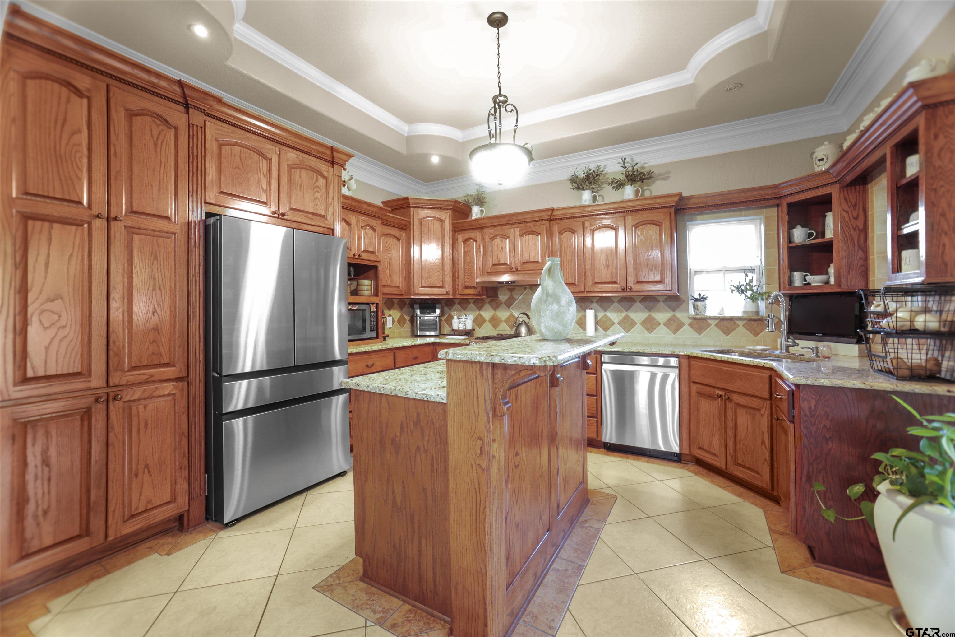 11931 State Highway 64 Tyler, TX 75704 - Photo 24 of 44 a kitchen with granite countertop stainless steel appliances a refrigerator a sink a stove a microwave a center island and cabinets
