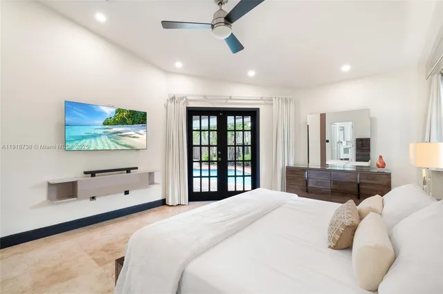 a bedroom with a large bed and a flat tv screen on dresser