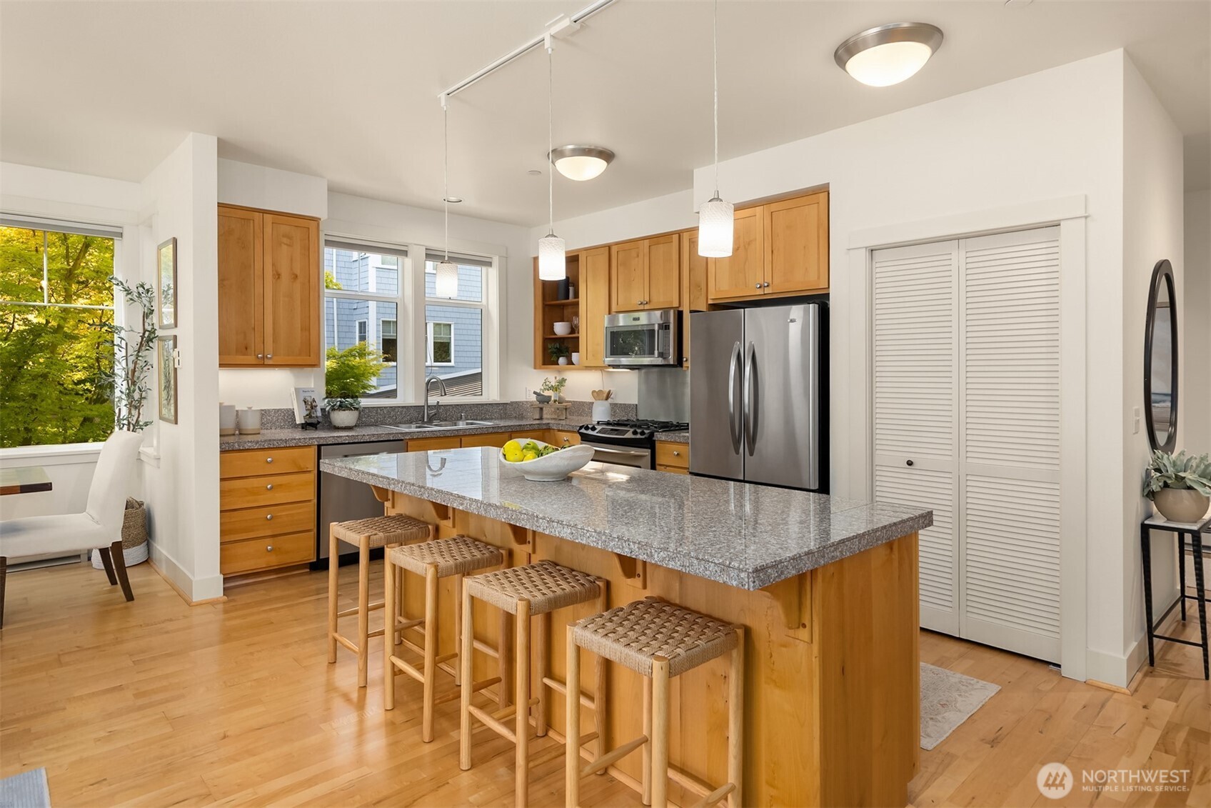 144 Hall Brothers Loop Northwest, Unit 101 Bainbridge Island, WA 98110 - Photo 12 of 30 a kitchen with stainless steel appliances granite countertop a refrigerator a stove a sink a dining table and chairs with wooden floor