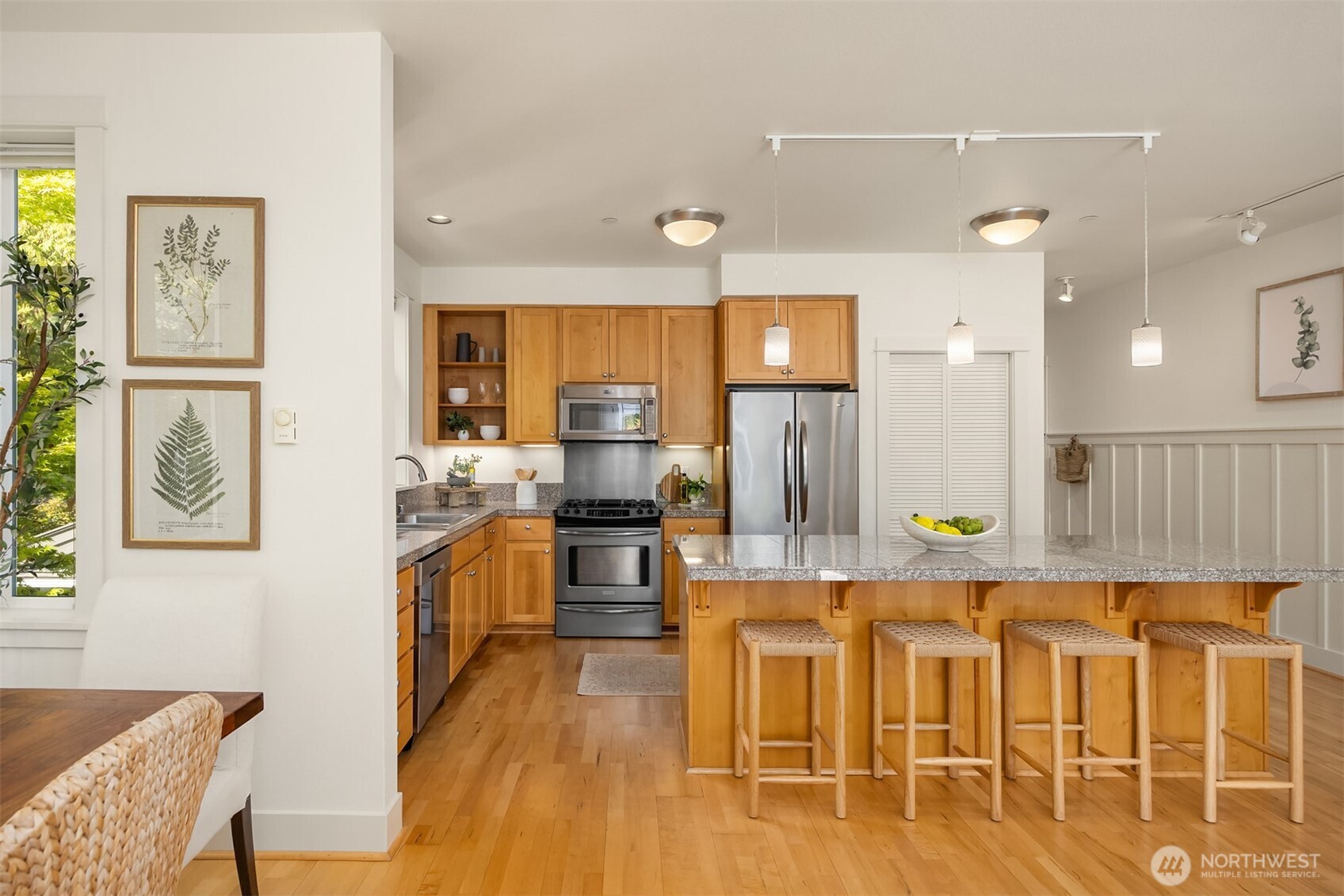 144 Hall Brothers Loop Northwest, Unit 101 Bainbridge Island, WA 98110 - Photo 14 of 30 a kitchen with stainless steel appliances kitchen island granite countertop a stove a refrigerator a sink a dining table and chairs with wooden floor