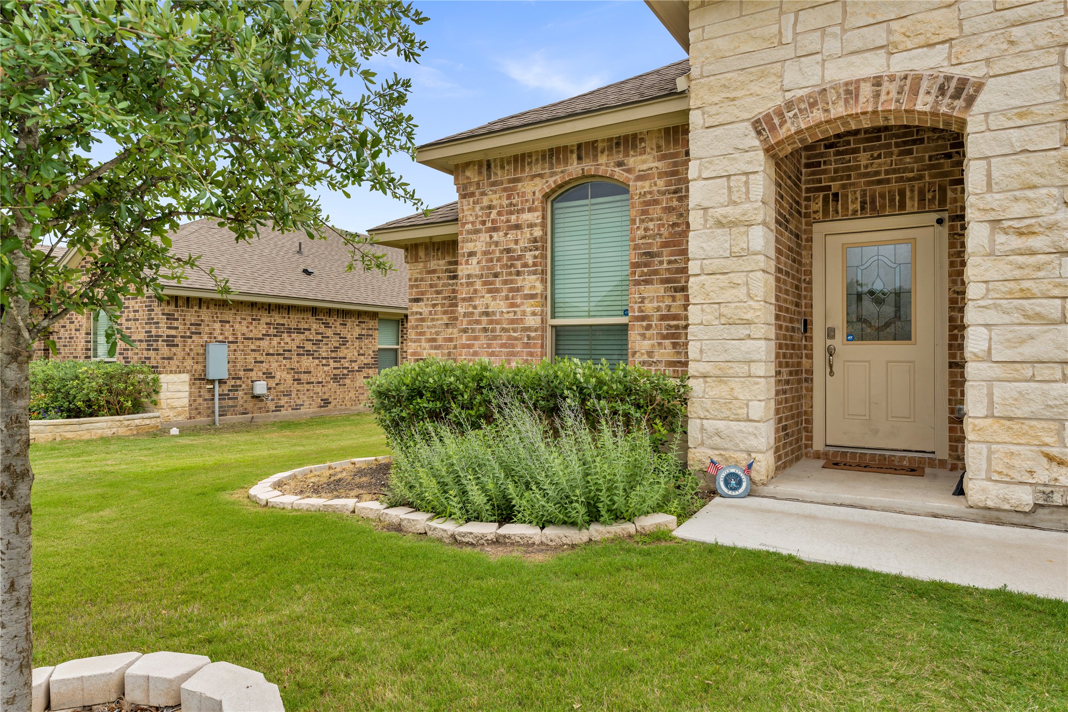 132 Cinnamon Loop Burnet, TX 78611 - Photo 3 of 27 Exterior showcasing a stone-clad entry arch and brick facade