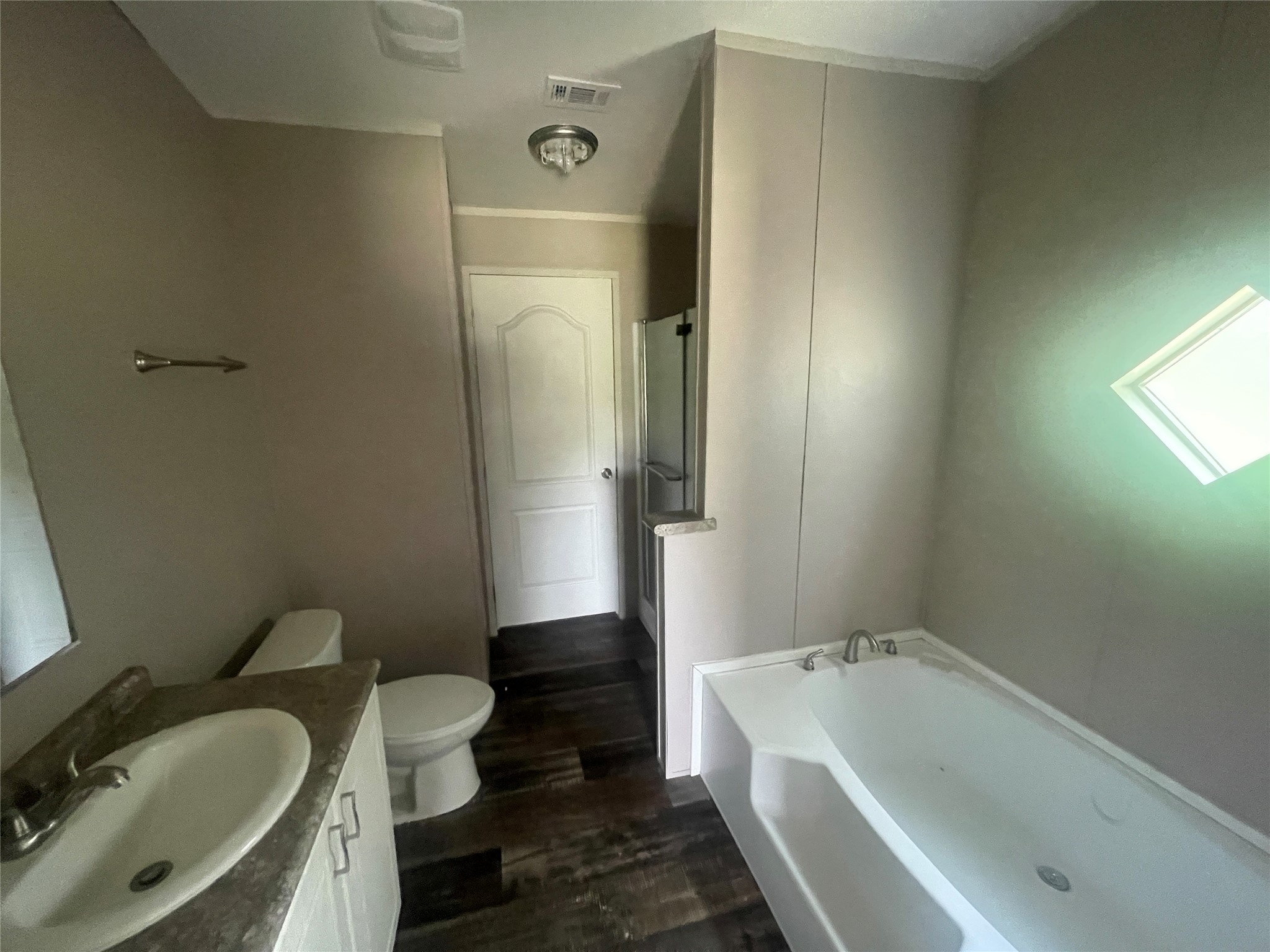 7855 Taylorsville Road Dale, TX 78616 - Photo 8 of 12 This bathroom offers a deep soaking tub and a separate shower, complemented by dark wood flooring.
