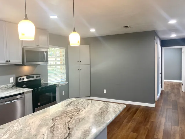 a kitchen with granite countertop a stove a sink and a wooden floors