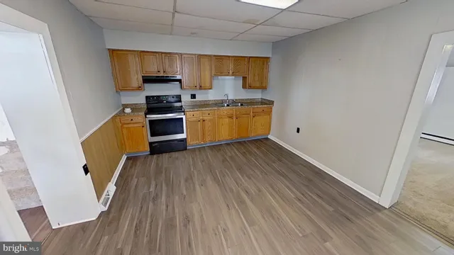 a kitchen with granite countertop wooden floors stainless steel appliances a sink and a window