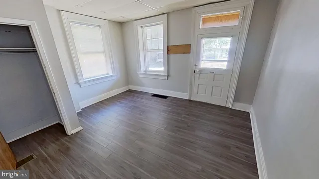 an empty room with wooden floor and windows