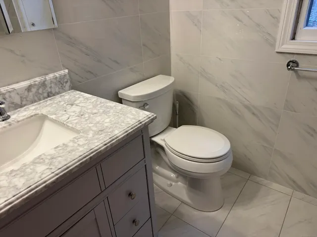 a bathroom with a granite countertop toilet and a sink