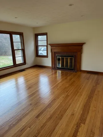 a view of a livingroom with wooden floor and a fireplace