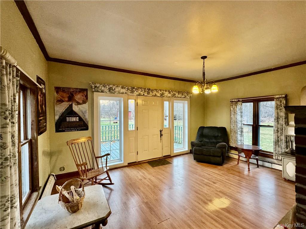 255 Howells Road Middletown, NY 10940 - Photo 8 of 38 Sitting room with baseboard heating, ornamental molding, a notable chandelier, and wood-type flooring