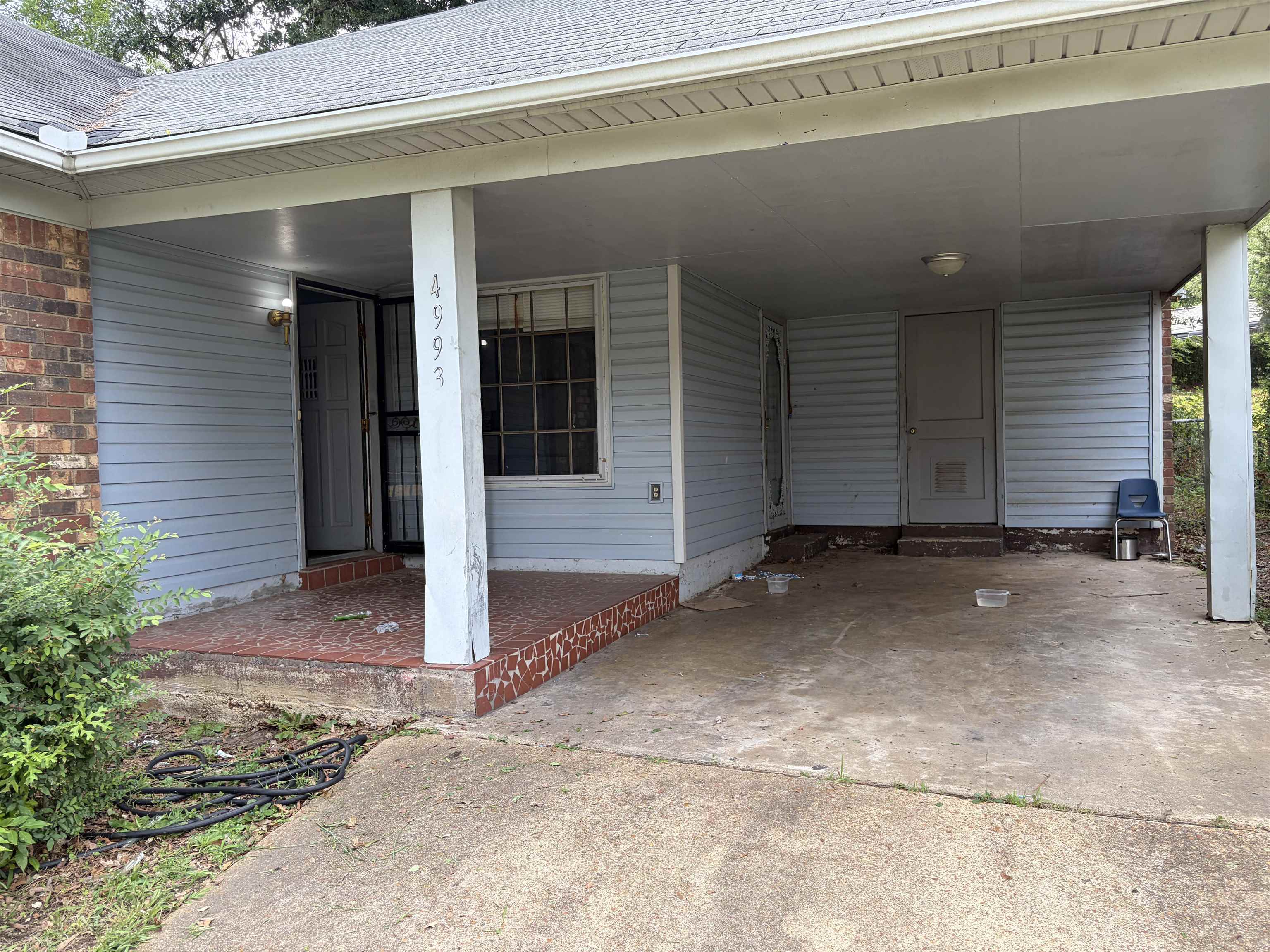 4993 Cedar View Road Memphis, TN 38118 - Photo 5 of 23 Covered carport entrance featuring light blue siding, brick accents, a gray shingled roof, and a concrete driveway