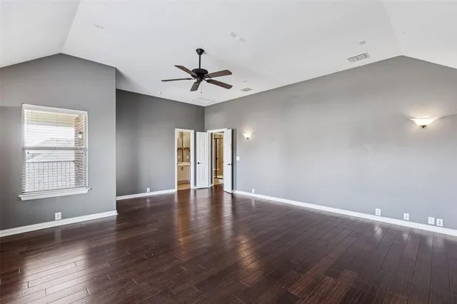 a view of an empty room with window and wooden floor