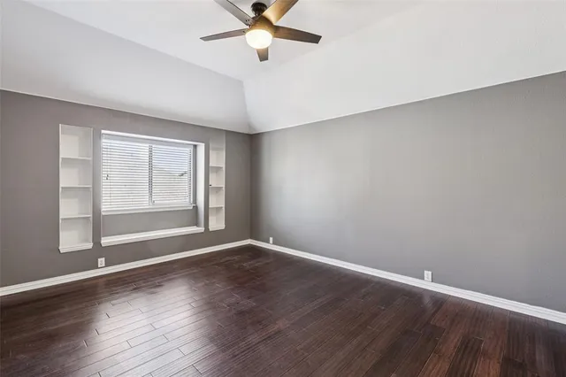 an empty room with wooden floor fan and windows