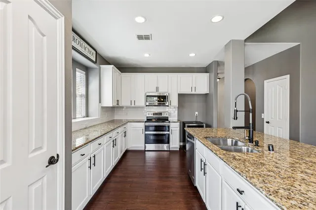 a large kitchen with stainless steel appliances granite countertop a sink stove and refrigerator
